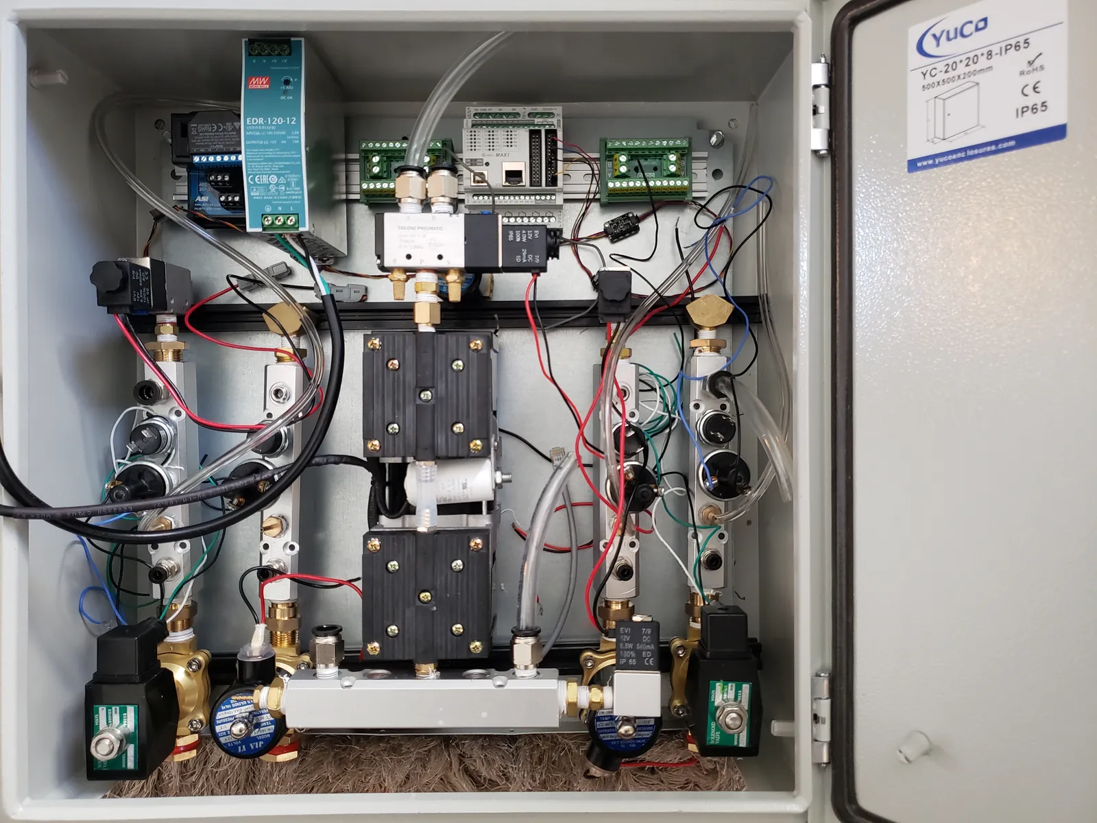 Open control enclosure with a DIN-rail power supply and controller, a pneumatic manifold, and brass solenoid valves on gas distribution blocks.